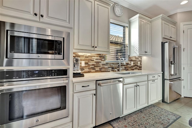 kitchen featuring tasteful backsplash, sink, white cabinets, light tile patterned floors, and stainless steel appliances