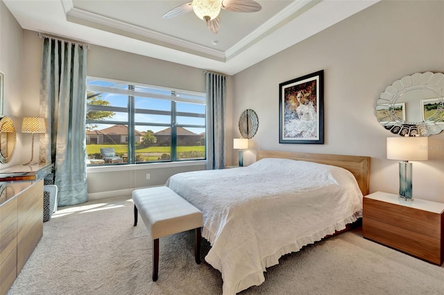 carpeted bedroom featuring a raised ceiling, ornamental molding, and ceiling fan