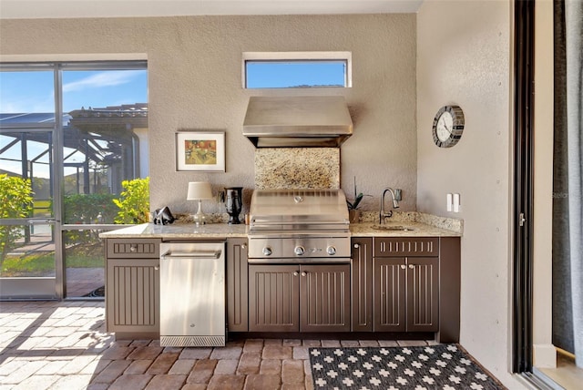 kitchen with sink, a wealth of natural light, light stone countertops, and wall chimney exhaust hood