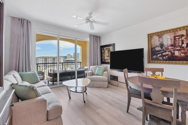 living room with ceiling fan, ornamental molding, and light hardwood / wood-style flooring