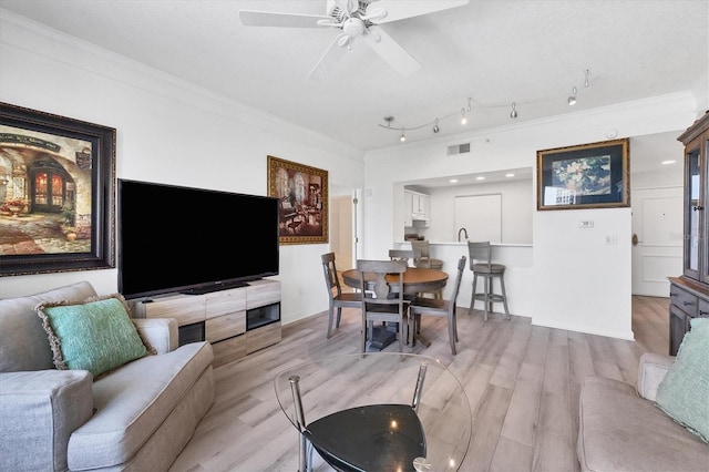 living room featuring light wood-type flooring, ceiling fan, and ornamental molding