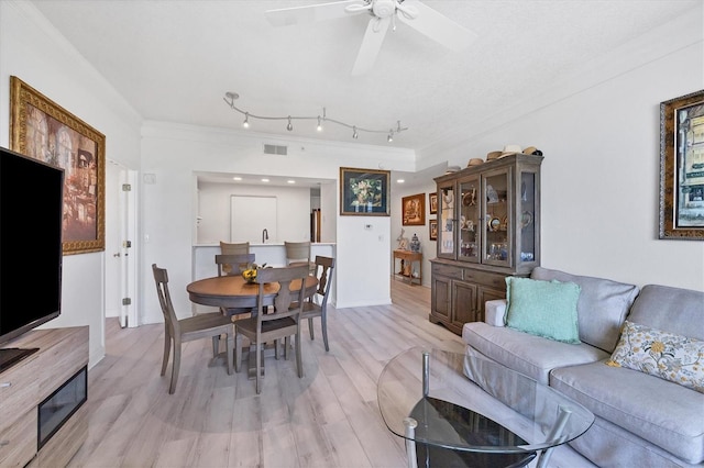 living room featuring ceiling fan, light hardwood / wood-style floors, and crown molding