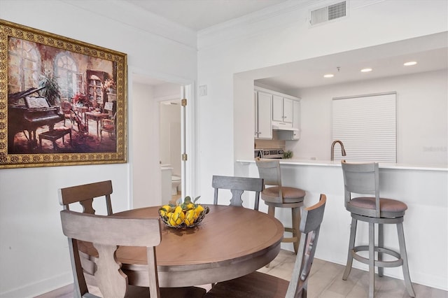 dining area featuring sink, ornamental molding, and light hardwood / wood-style floors