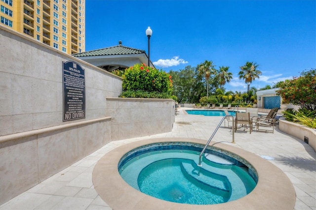 view of swimming pool featuring a community hot tub and a patio