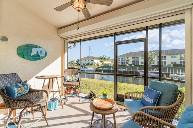 sunroom featuring lofted ceiling, ceiling fan, and a water view