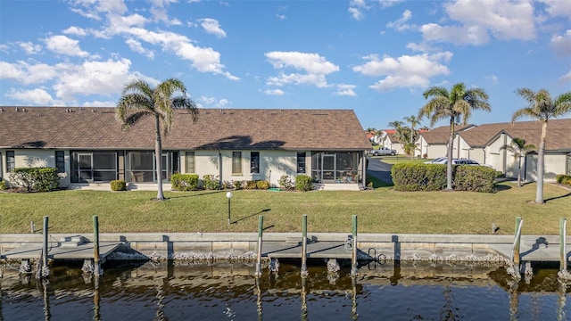 back of property with a lawn and a water view