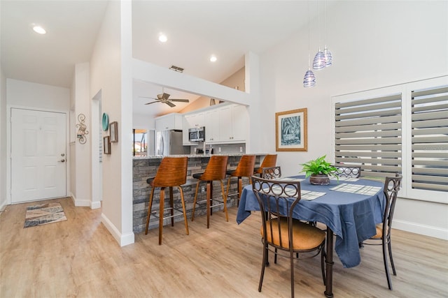 dining space featuring high vaulted ceiling, light wood-type flooring, ceiling fan, and a healthy amount of sunlight