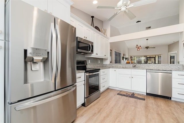 kitchen with stainless steel appliances, white cabinets, decorative light fixtures, lofted ceiling, and ceiling fan