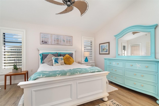 bedroom with ceiling fan, light wood-type flooring, and lofted ceiling