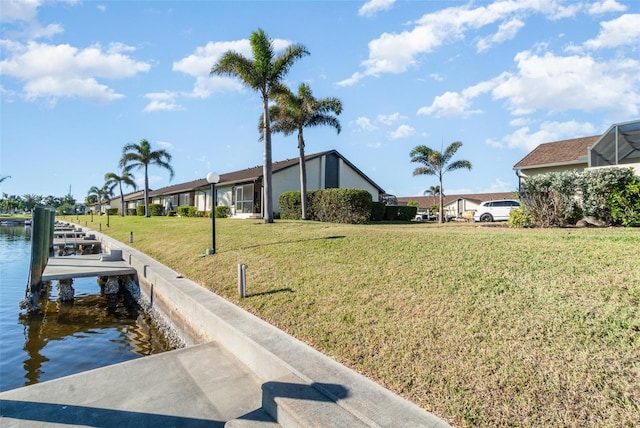 view of dock with a yard and a water view