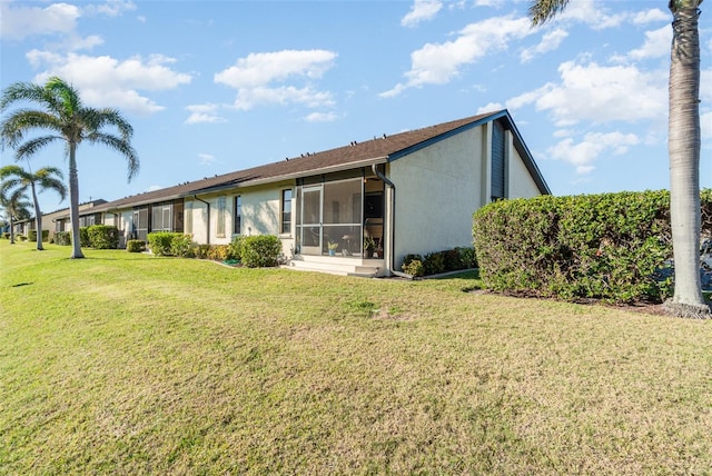 rear view of house with a yard and a sunroom