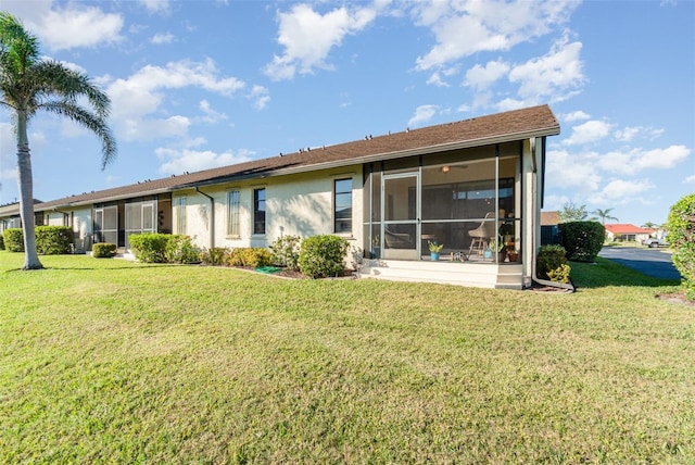 back of property with a yard and a sunroom