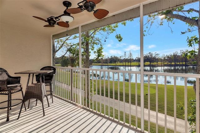 sunroom / solarium featuring ceiling fan and a water view