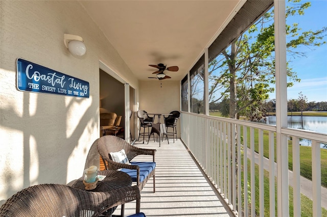 sunroom featuring ceiling fan and a water view