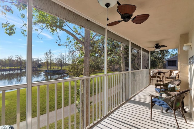 sunroom / solarium with ceiling fan and a water view