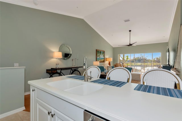 kitchen featuring lofted ceiling, crown molding, white cabinets, ceiling fan, and sink