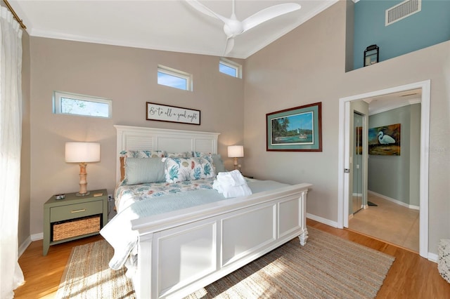 bedroom featuring ceiling fan, light hardwood / wood-style floors, a towering ceiling, and crown molding