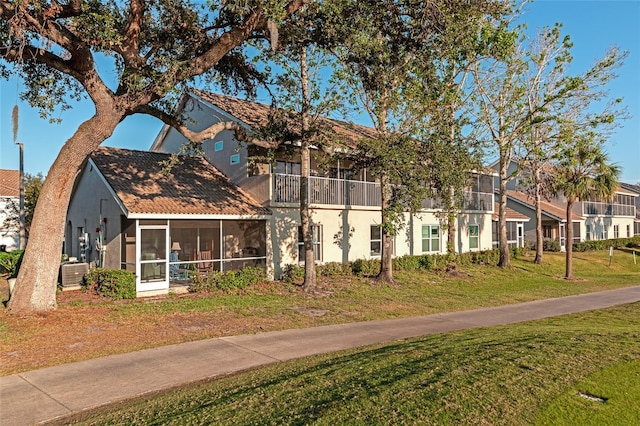 view of front of house with cooling unit, a front lawn, and a sunroom