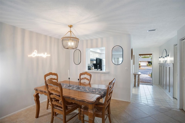 dining area featuring a textured ceiling, a notable chandelier, and light tile patterned floors