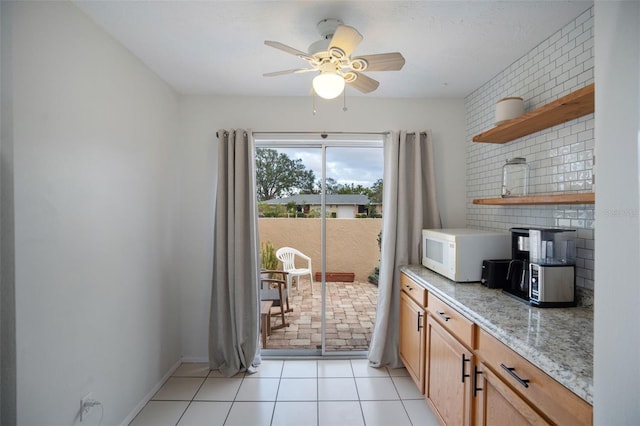 kitchen featuring ceiling fan, light tile patterned floors, and light stone counters