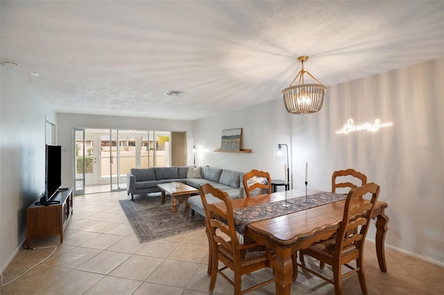 dining room with a textured ceiling, a notable chandelier, and light tile patterned floors