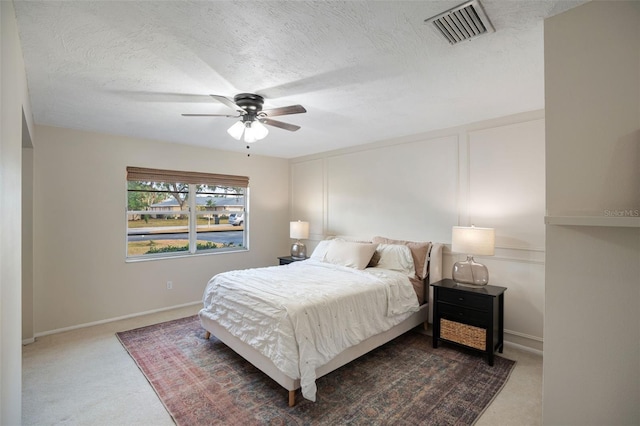 carpeted bedroom featuring ceiling fan and a textured ceiling