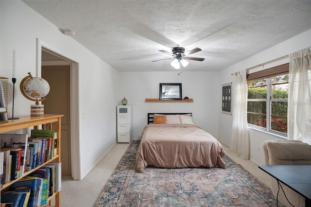 bedroom with a textured ceiling, ceiling fan, and light carpet