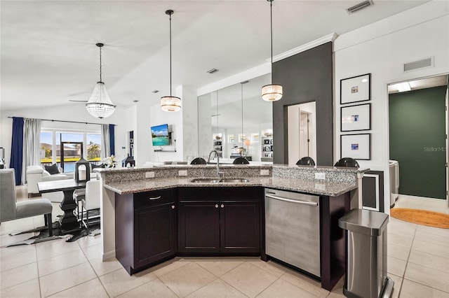 kitchen featuring a kitchen island with sink, sink, light stone counters, and hanging light fixtures