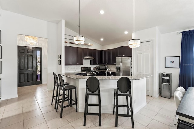 kitchen featuring dark brown cabinetry, hanging light fixtures, a breakfast bar, and appliances with stainless steel finishes