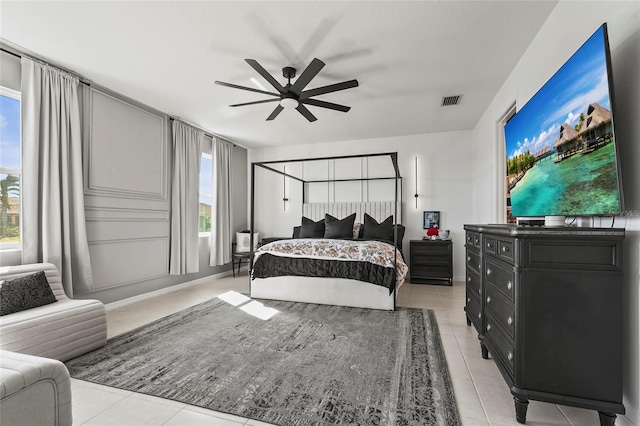 tiled bedroom featuring ceiling fan and multiple windows