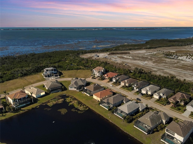 aerial view at dusk featuring a water view