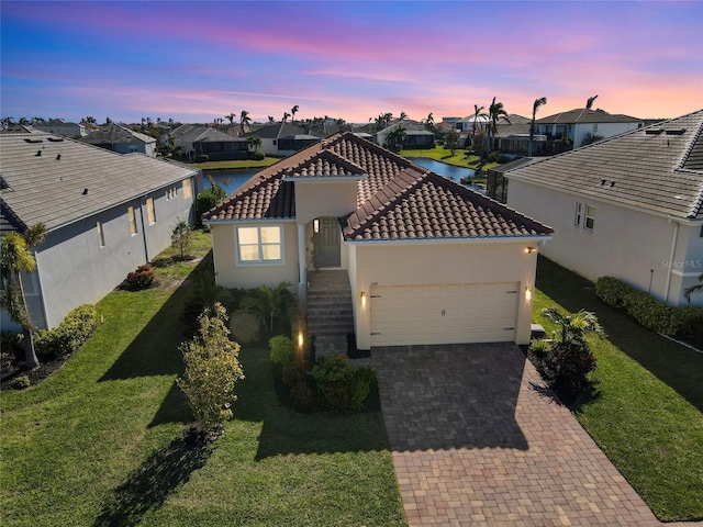 view of front facade featuring a yard, a garage, and a water view