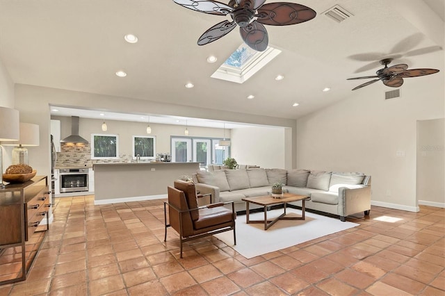 tiled living room with a tile fireplace, lofted ceiling with skylight, and ceiling fan