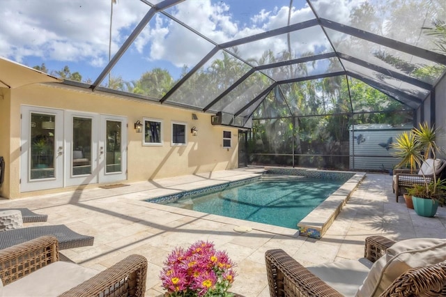 view of swimming pool featuring a lanai, a patio, french doors, and a storage shed