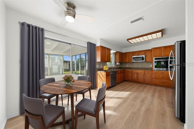 kitchen featuring light hardwood / wood-style floors, tasteful backsplash, appliances with stainless steel finishes, ceiling fan, and sink