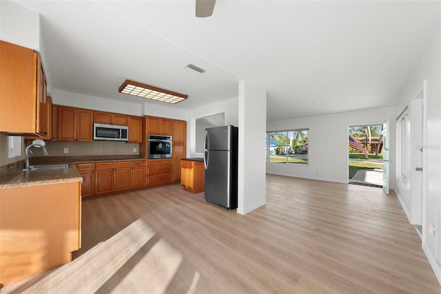 kitchen featuring stainless steel appliances, sink, ceiling fan, and light wood-type flooring