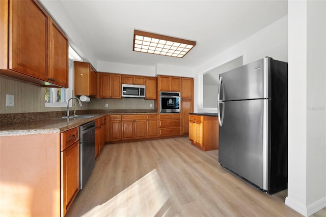 kitchen with stainless steel appliances, sink, light hardwood / wood-style floors, and tasteful backsplash