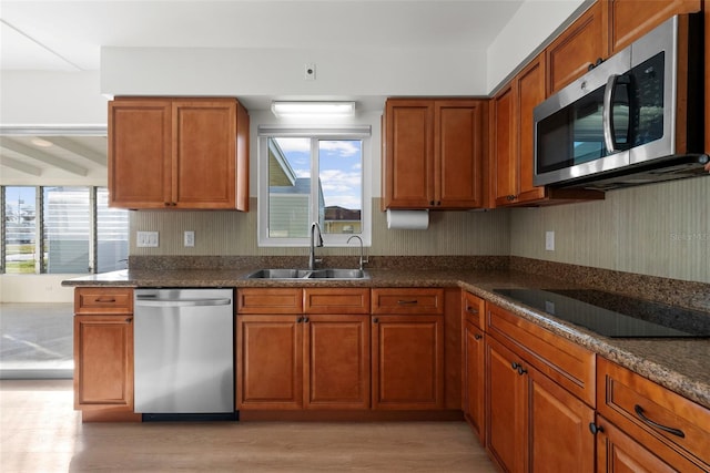 kitchen with sink, dark stone countertops, a healthy amount of sunlight, and appliances with stainless steel finishes