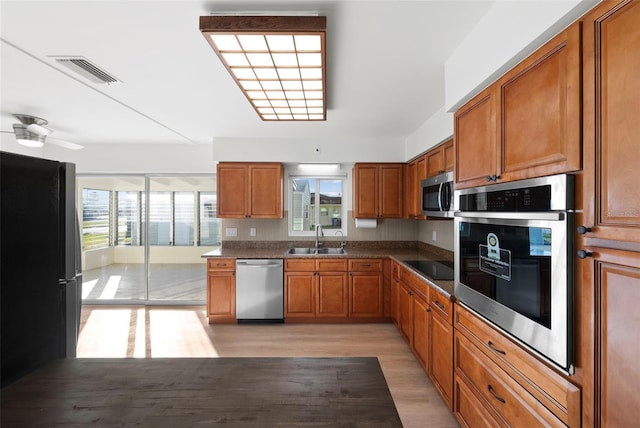 kitchen featuring stainless steel appliances, sink, ceiling fan, and light hardwood / wood-style flooring