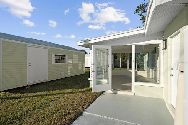 view of exterior entry with a patio and a lawn