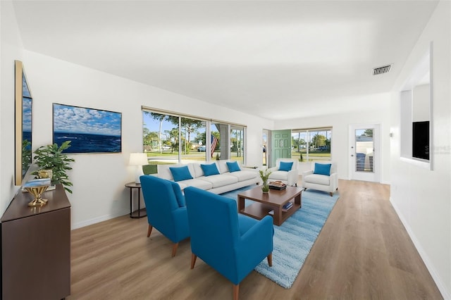 living area with wood finished floors, visible vents, and baseboards