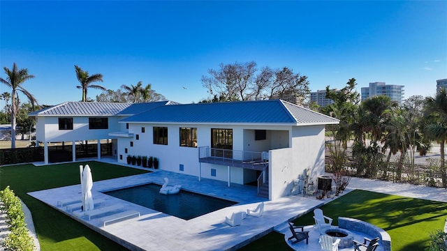 back of property with a balcony, a lawn, cooling unit, a fire pit, and a patio