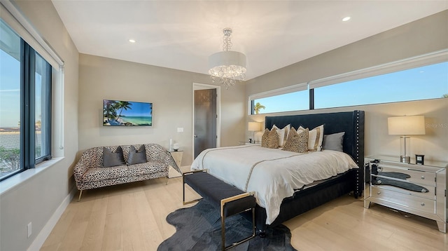 bedroom featuring an inviting chandelier and light hardwood / wood-style flooring