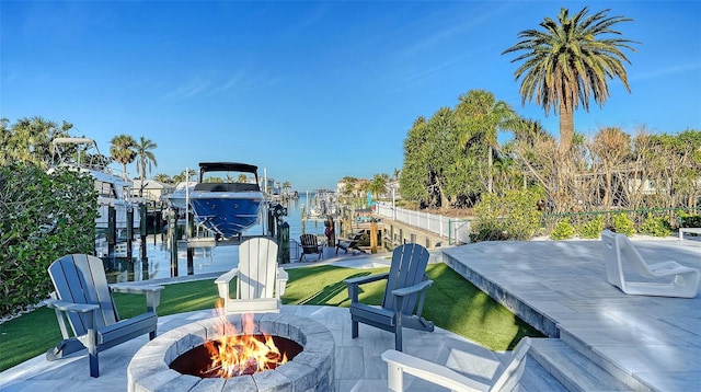 view of patio with a water view, a boat dock, and a fire pit