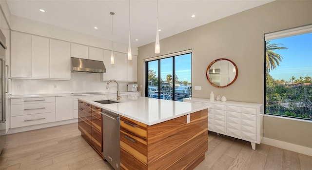 kitchen featuring sink, a kitchen island with sink, white cabinetry, decorative light fixtures, and stainless steel dishwasher