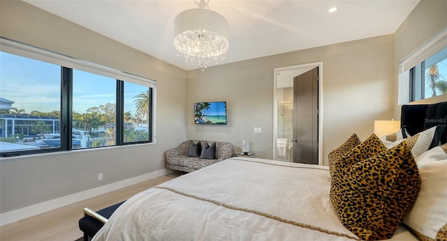 bedroom with multiple windows, a chandelier, and light hardwood / wood-style flooring