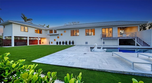 back of property with a lawn, a patio, and a balcony