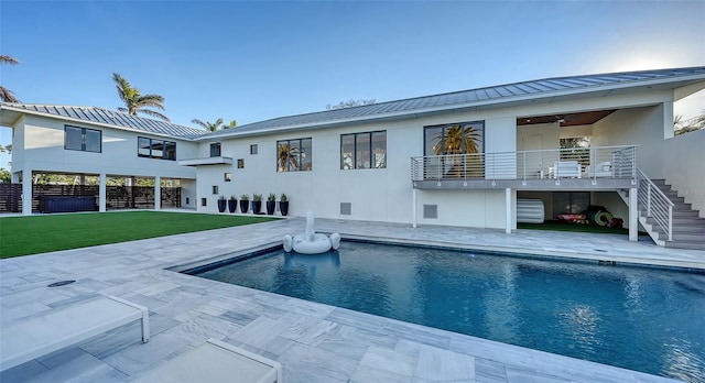 rear view of property featuring stucco siding, stairway, a lawn, and a patio