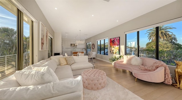 living area with light wood-type flooring, an inviting chandelier, baseboards, and recessed lighting