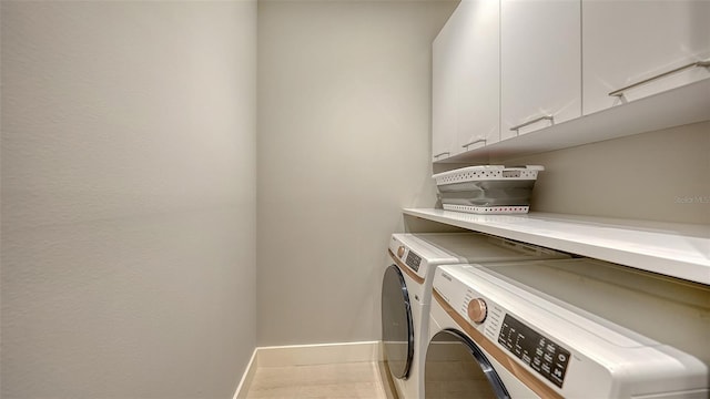 clothes washing area with baseboards, cabinet space, and washer and dryer